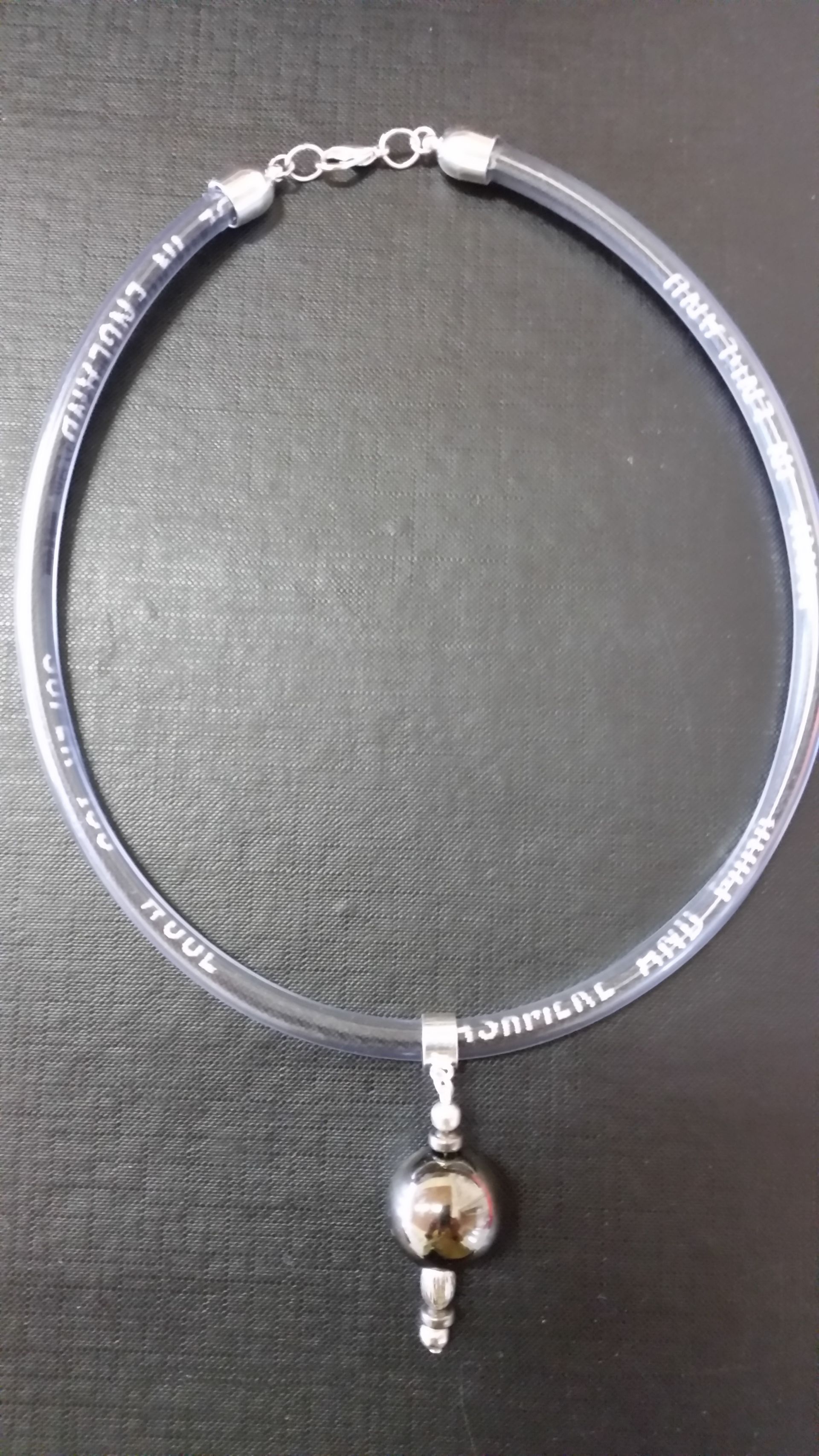 Silver Ball necklace ‘time capsule’ containing the embroidered selvedge of beautiful old FJ fabrics, often never seen.  Artist and Photo: Helen Bunyon.